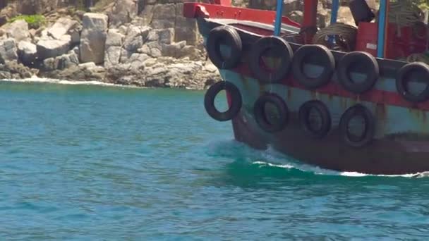 Navio flutuando com pneus de carro a bordo em mar azul na paisagem da montanha penhasco. Barco navegando na água do mar azul-turquesa, penhasco rochoso e fundo da montanha . — Vídeo de Stock