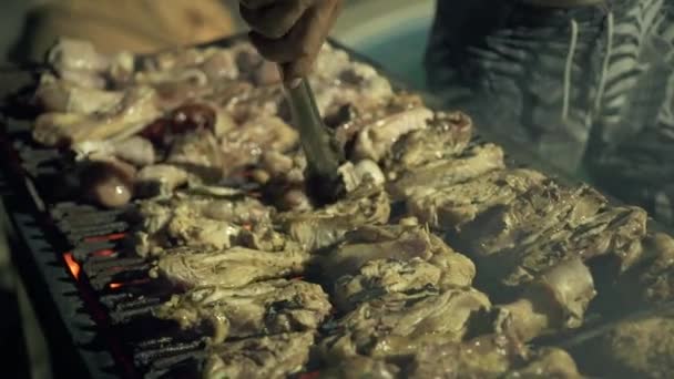 Männer, die draußen am Grill Fleischbraten zubereiten. close up Prozess Vorbereitung Grillfleisch auf dem Grill auf Feuer und Kohle. Kochkonzept. — Stockvideo