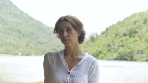 Chica retrato en el río de verano y paisaje de montaña verde. Rostro joven en la orilla del lago y la montaña cubierta de bosque verde fondo . — Vídeos de Stock