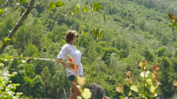 Mujer joven de pie sobre fondo verano montaña cubierta bosque verde. Chica disfrutando de verde paisaje de montaña mientras que los viajes de verano . — Vídeos de Stock