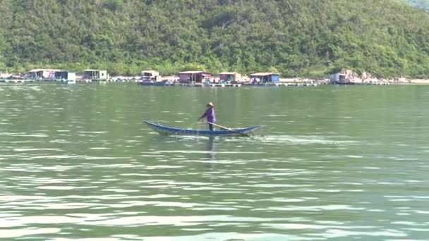 Nha Trang, Vietnam - octubre de 2018: pescador en barco pescando con red de pesca en mar azul sobre fondo verde de montaña. Los hombres la captura de peces con red en el mar . — Vídeo de stock