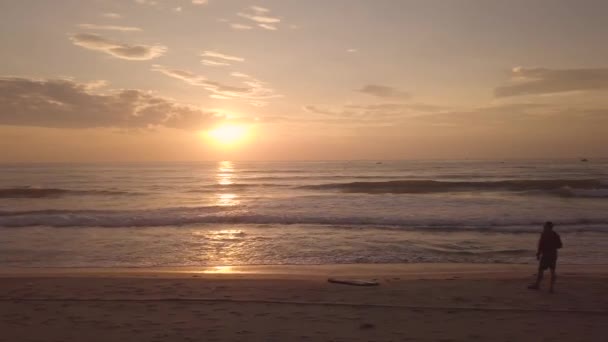 Nascer do sol de manhã cedo no céu na praia de verão vista aérea. As pessoas observam o amanhecer da manhã no céu dourado na praia de areia. Drone vista pôr do sol sobre a água do mar . — Vídeo de Stock
