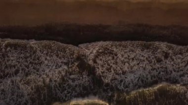 Altın günbatımı hava görünümünü ise kum plajındaki sıçramasına beyaz köpüklü su dalgalar deniz. TOPVIEW okyanus dalgalar kıyıya ve akşam güneş su yüzey yansıtan üzerinde.
