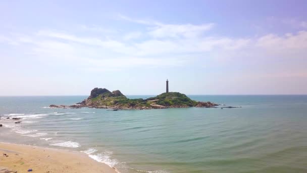 Phare sur l'île de falaise dans la vue bleue de drone de mer. Vue aérienne maison lumineuse sur une île rocheuse dans l'océan et ciel bleu paysage . — Video