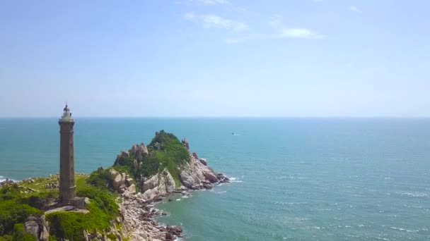 Farol na ilha rochosa em azul mar paisagem aérea. Drone view light house on cliff in ocean on blue water and sky background . — Vídeo de Stock