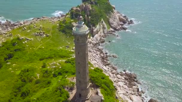 Farol na costa do mar e paisagem aérea de água azul de drone voador. Casa clara na costa rochosa na vista azul do drone do oceano . — Vídeo de Stock