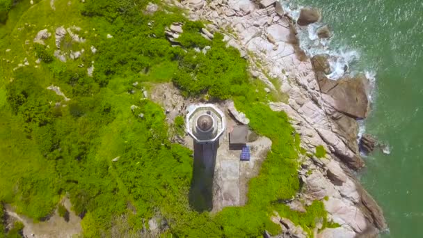 Bovenaanzicht zee vuurtoren op rotsachtige eiland in de blauwe zee. Luchtfoto landschap vuurtoren op groene oever in Oceaan. — Stockvideo