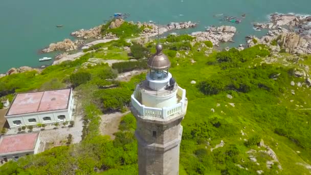 Widok z lotu ptaka na morze latarni na skalistej wyspie na błękitne morze i nowoczesne miasto, na panoramę. Drone widok wieża latarni na zielonej wyspie w ocean. — Wideo stockowe