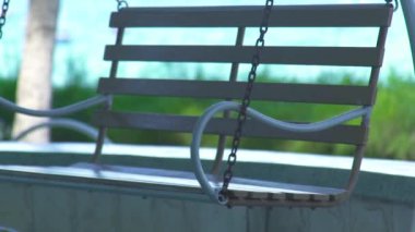 Yaz plaj mavi deniz ve yeşil bitkiler peyzaj üzerine salıncak. Mavi deniz, palmiye ağacı ve yeşil bitkiler artalan üzerinde hareketli sallanan.