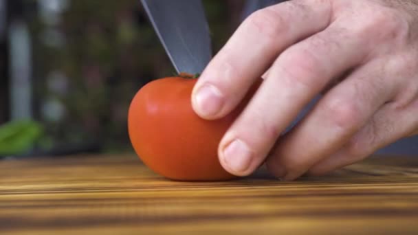 Close-up van de verse tomaat snijden op houten tafel. Chef-kok koken cuting rode tomaat aan boord van de keuken. Plantaardige en vegetarische maaltijden. Gezonde voeding en fitness voeding. Ingrediënt voor groente salade. — Stockvideo