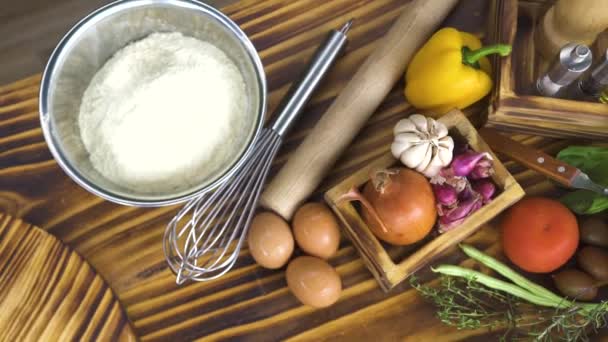 Πλάνο παρακολούθησης αλεύρι αυγά, φρέσκα λαχανικά και τυρί για το μαγείρεμα πίτσα. Σύνθεση των τροφίμων από το συστατικό για ιταλικά ζυμαρικά. Λαχανικό στον ξύλινο τραπέζι. Το Top view σύνθεση των τροφίμων. Μαγειρική έννοια. — Αρχείο Βίντεο