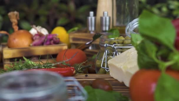 Seguimiento de la composición de los alimentos tiro de cerca. Fondo alimentario de verduras, aceitunas, hierbas, queso, condimentos en mesa de madera. Ingredientes frescos para cocinar en la mesa de la cocina. Dieta saludable y nutrición . — Vídeo de stock