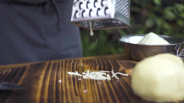 Ralar queijo no ralador de perto. Chef cozinheiro ralar queijo fresco para a preparação de alimentos cozinha mediterrânea. Ingredientes para pizza italiana ou salada grega. Processo de cozinhar alimentos na cozinha . — Vídeo de Stock