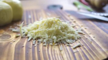 Rendelenmiş peynir ahşap masa portre üzerinde düşüyor. Peynir rende üzerinde ızgara işlemi. Yemek makarna, pizza, salata, lazanya için taze madde. Akdeniz, İtalyan ve Yunan mutfağı. Yemek pişirmek kavramı