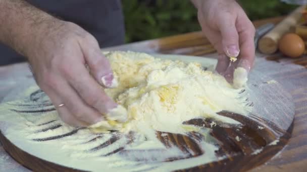 Mão de cozinheiro cozinheiro chef amassar massa com farinha e ovos de galinha em tábua de madeira. Baker fazendo massa para torta na mesa da cozinha. Processo de fazer pastelaria para pizza ou massa. Produtos de panificação de preparação . — Vídeo de Stock