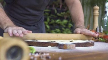 Çalışırken ince hamur rulo pasta ahşap tahta üzerinde için yemek. İşlem'de ekmek tabloda silindir iğne ile Hamur Mayaları haddeleme. Hamur işi, pasta, pizza ve makarna pişirme. Hazırlık ev yapımı yiyecek konsepti.