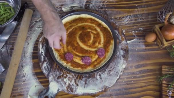 Chef cuisinier vue de dessus faisant pizza avec pepperoni saucisse dans la cuisine pizzeria, farine sur table en bois. Pizzaillo préparant une pizza dans un restaurant italien. Cuisine italienne traditionnelle. Concept de cuisine alimentaire . — Video