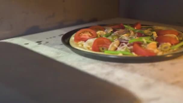 Pizza cruda con queso, tomates y pepperoni cocinando en horno caliente en la cocina de la pizzería. Cocción de pizza tradicional en el moderno restaurante italiano estufa. Cocina nacional, cocina tradicional . — Vídeo de stock