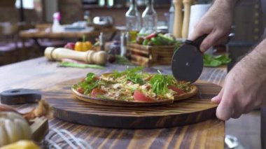 El aşçı kesme pizza ahşap masa, gıda arka plan üzerinde bıçakla. Lokanta mutfağı sıcak pizza Dilimleme işlemini kapatın. Geleneksel İtalyan. Gıda ve snack kavramı.
