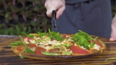 Pizzacı ahşap tablo silindir bıçaklı kesme pizza dilimleri üzerine kapatın. Şef yemek İtalyan restoranında sıcak pizza dilimleme. Hazırlık geleneksel İtalyan yemekleri. Ulusal gıda kavramı.