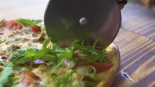 Cocinero cocinero cortando pizza con cuchillo de rodillo en mesa de madera en pizzería. Cerrar pizzaillo cortar pizza caliente en rebanadas en restaurante italiano. Proceso de preparación de comida italiana tradicional. Concepto alimenticio . — Vídeos de Stock