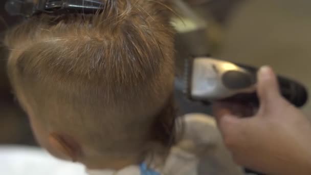 Kinder schneiden Konzept. Friseur schneidet Haar kleiner Junge mit Rasiermesser in Friseursalon. Kinderhaarschnitt mit Haarmaschine aus nächster Nähe. Friseur frisiert Kinder im Friseursalon. — Stockvideo