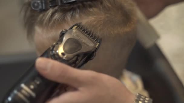 Cutting little boy with electrical shaver in children hairdressing salon. Children hairdresser doing boy hairstyle with electric razor in barber shop close up. Kids haircut, beauty, fashion concept. — Stock Footage Cutting little boy with electrical shaver in children hairdressing salon. Children hairdresser doing boy hairstyle with electric razor in barber shop close up. Kids haircut, beauty, fashion concept. Video Clip