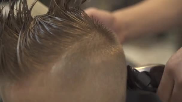 Mannelijke kapper met behulp van elektrische scheerapparaat voor kinderen kapsel. Portret jongetje terwijl kappers met haar machine in de barbershop van de kinderen. Haarstylist snijden jongen, kind kapsel in salon. — Stockvideo