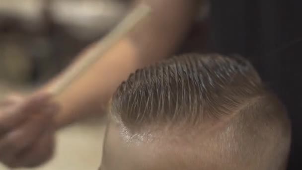 Cabeleireiro pentear cabelo molhado menino e corte com navalha elétrica na barbearia. Cabeleireiro fazendo crianças corte de cabelo com aparador no salão de cabeleireiro. Kid penteado conceito . — Vídeo de Stock