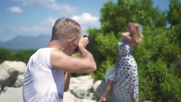 Mężczyzna fotografa przy fotografii młoda kobieta pozowanie odkryty. Młody człowiek pracy z modelu profesjonalnego fotografa. Człowiek za pomocą aparatu fotograficznego dla sesja zdjęciowa pięknej kobiety. — Wideo stockowe