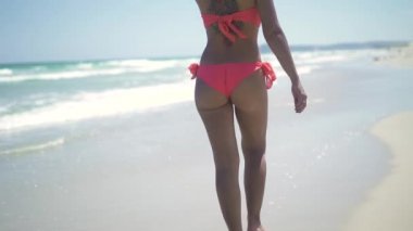 Deniz mavi su manzara kumsalda yürürken Bikini güzel bir kadın. Seksi çekici genç kadın dövme yaz deniz plaj ve mavi deniz manzara.