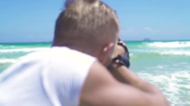 Adam fotoğrafçı fotoğraf genç kadının bikini deniz sahilde poz alarak. Genç kadın modeli ile denizde çalışan fotoğrafçı adam. Adam güzel kadının fotoğraf oturumu için fotoğraf makinesi kullanma.