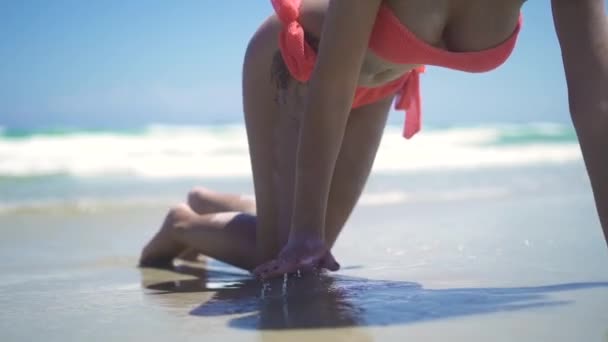 Junge Frau im Bikini und Tätowierung am Sandstrand vor blauer Meereslandschaft liegend. sexy schöne Frau im Sommer-Bikini liegt am Meeresstrand und türkisfarbenem Wasser Hintergrund. — Stockvideo