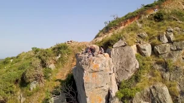 Vandrare som sitter på kanten berget ovanför havet landskapet. Flygfoto turist njuter av landskapet av blå havet från cliff. Utsikten från bergstoppen på blå havet vatten. — Stockvideo