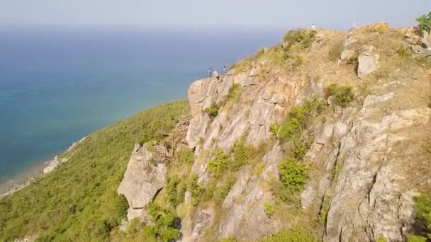 Touristen auf Klippen mit blauer Meereslandschaft. Luftaufnahme von türkisfarbenem Meer und Bergen. Drohnenblick blaue Meereslandschaft vom Berggipfel. — Stockvideo
