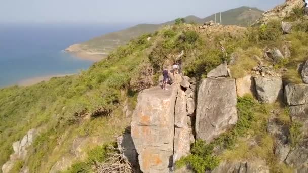 Toeristen op rand berg boven zee landschap drone weergave. Wandelaars op de bergtop met blauwe zee landschap. Mensen op de rand van de klif met uitzicht op turquoise Oceaan luchtfoto schot. — Stockvideo