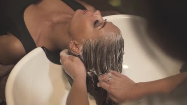 Mladá žena přijímá mytí hlavy v salonu krásy. Kadeřník ruční mytí ženské hlavy zblízka. Péče o vlasy v kadeřnictví. Kadeřník mytí vlasů. Krása a účes. — Stock video