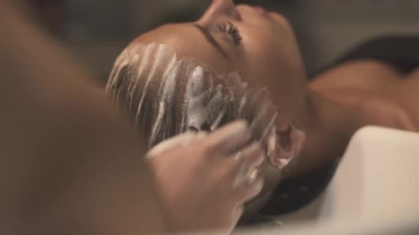 Kapper wasmachine vrouw haargroei en hoofd in schoonheid studio voordat kapsel. Close-up Haarstylist wassen hoofd met massage in de kapsalon. Jonge vrouw in de schoonheidssalon. Behandeling en spa zorg. — Stockvideo