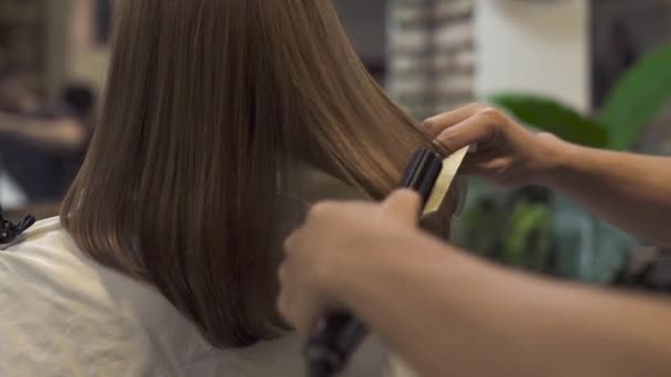 造型师矫直长发与铁和梳理 而发型在美发沙龙 妇女发型与头发铁在美容工作室 大师创造女性发型在理发店 — 图库视频影像