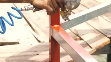 Boya tabancası uygulamak için kahverengi boya metal parçalar kullanarak ustası. Boya püskürtme ve kompresör ile alt resim metal çit. Boyama ekipman. Onarım ve restorasyon çalışmaları.