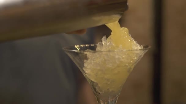 Cocktail di versamento di barista da shaker in vetro con ghiaccio tritato al bancone di bar in ristorante. Barman fare cocktail su shaker e versando in vetro sul tavolo del bar nel bar pub . — Video Stock