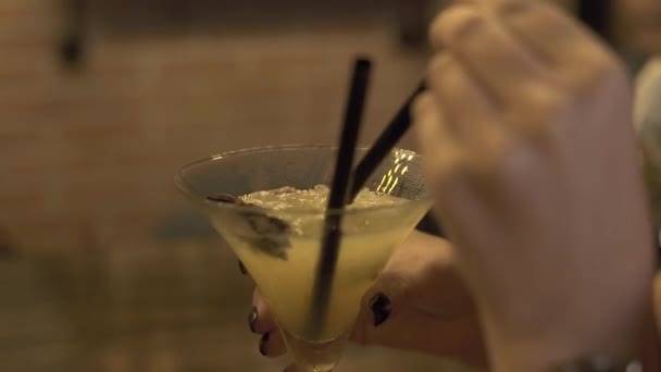 Молодая женщина пьет алкогольный коктейль из соломы за барной стойкой в ресторане. Закройте красивую женщину, пьющую коктейль из стекла в баре . — стоковое видео