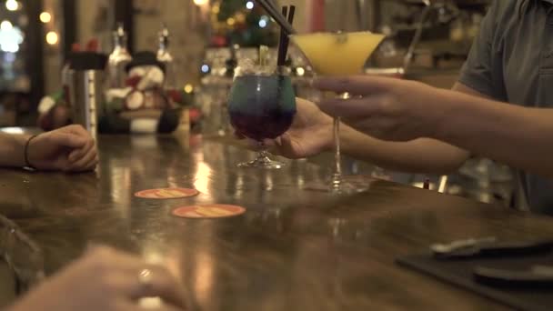 Barman dávat alkoholický koktejl v baru stůl pro klienta v kavárně večer. Lidé, kteří užívají koktejlové sklenice long drink, sedící u baru v restauraci. — Stock video