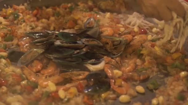 Kocken förbereder Spanien paella med ris och färska skaldjur i stekpanna på nära håll. Traditionell spansk maträtt paella med blåmusslor, räkor, calamari och grönsaker. Mat matlagning koncept. Hälsosam kost. — Stockvideo
