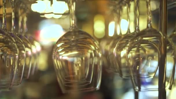 Wine glasses for drinking cocktail hanging above bar rack in restaurnt. Close up empty glasses for wine and alcoholic cocktail on bar counter in pub. — Stock Video