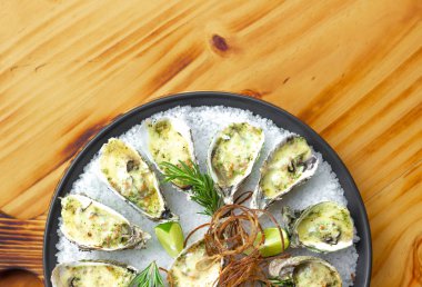 İstiridye peynir ve ahşap arka plan üzerinde plaka üzerinde otlar pişmiş. Deniz ürünleri arka plan kopya alanı. Deniz ürünleri ile Akdeniz mutfağı. Restoran menü ve gıda kompozisyonu.