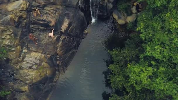 Gente turística buceando y nadando en cascada de montaña en el paisaje aéreo de la selva tropical. Gente saltando en el agua del río que fluye de la cascada de montaña en la selva . — Vídeo de stock