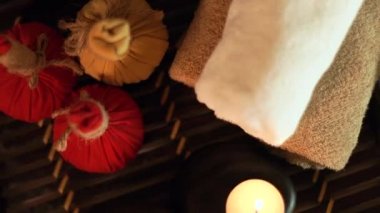 Mumlar yanan spa, taşlar için vücut masaj aksesuarları, aromatik otlar ve havlu. Üstten Görünüm. Mum ve masaj salonu içinde taşlar ile Spa dekorasyon. Vücut ve cilt bakım kavramı.