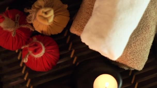 Accesorios de spa velas encendidas, piedras para masaje corporal, hierbas aromáticas y toallas. Vista superior. Decoración del spa con velas y piedras en el salón de masajes. Concepto de cuidado corporal y cutáneo . — Vídeo de stock