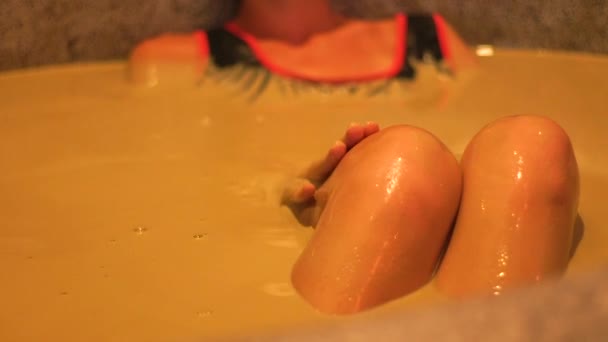 Mujer joven tomando baño de barro para la terapia de la piel y el cuidado del cuerpo. Chica relajante y disfrutando de spa de barro. Concepto saludable y de belleza. Balneario y terapia mineral . — Vídeos de Stock